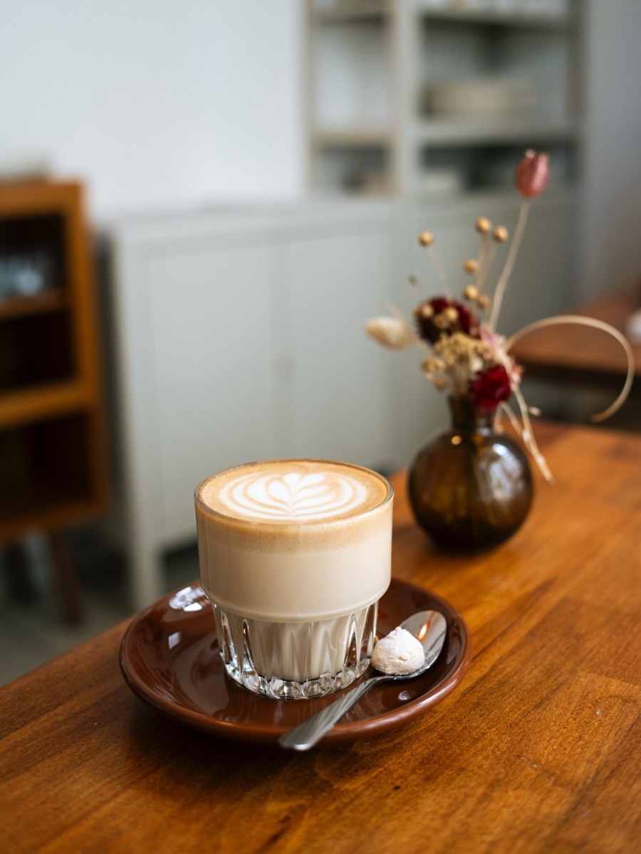 Cappuccino mit Latte Art auf Holztisch im Café Per Tutti